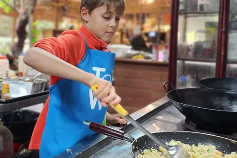 A young traveller stir-frying rice in a wok at a cooking class